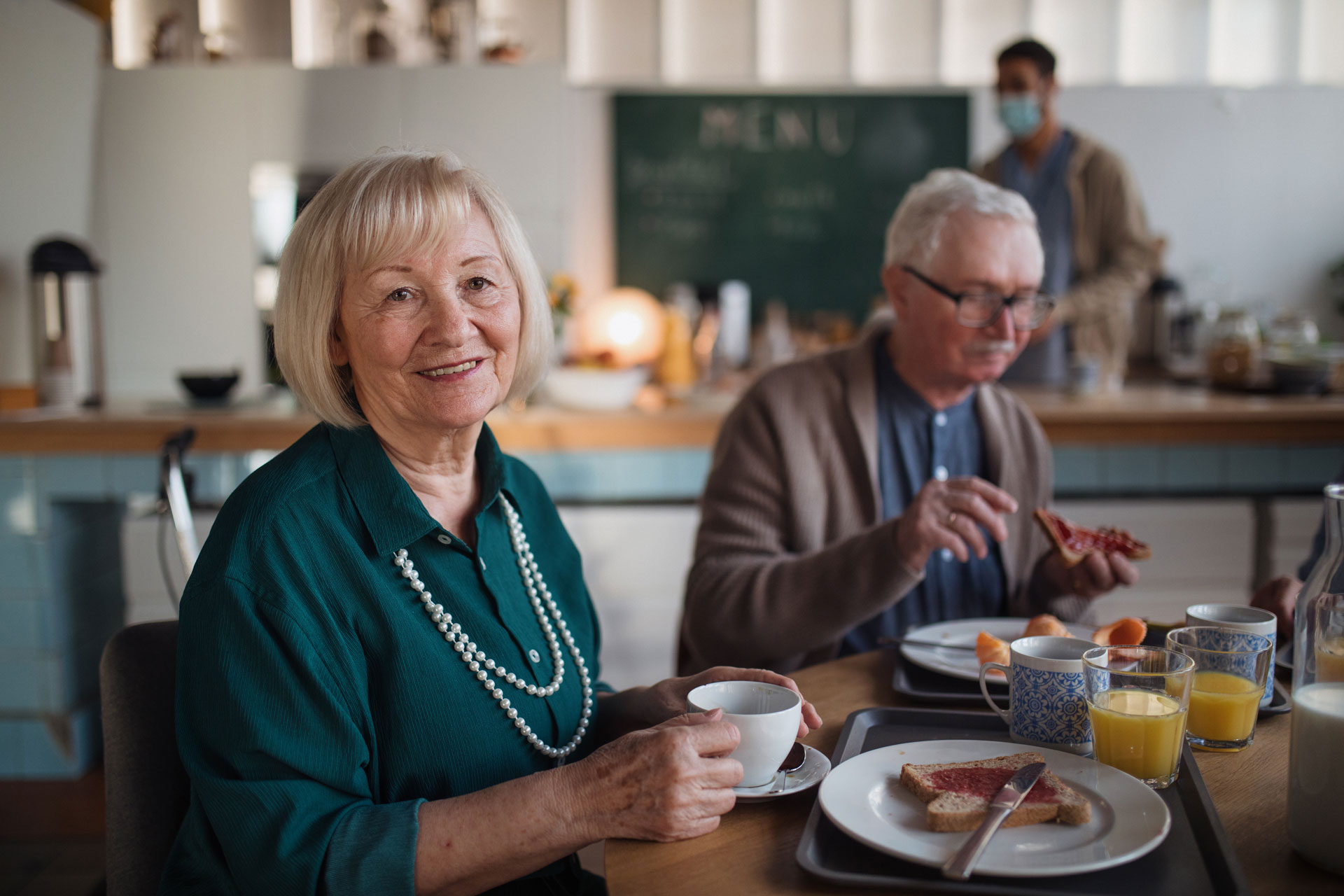 resident eating breakfast with others and smiling